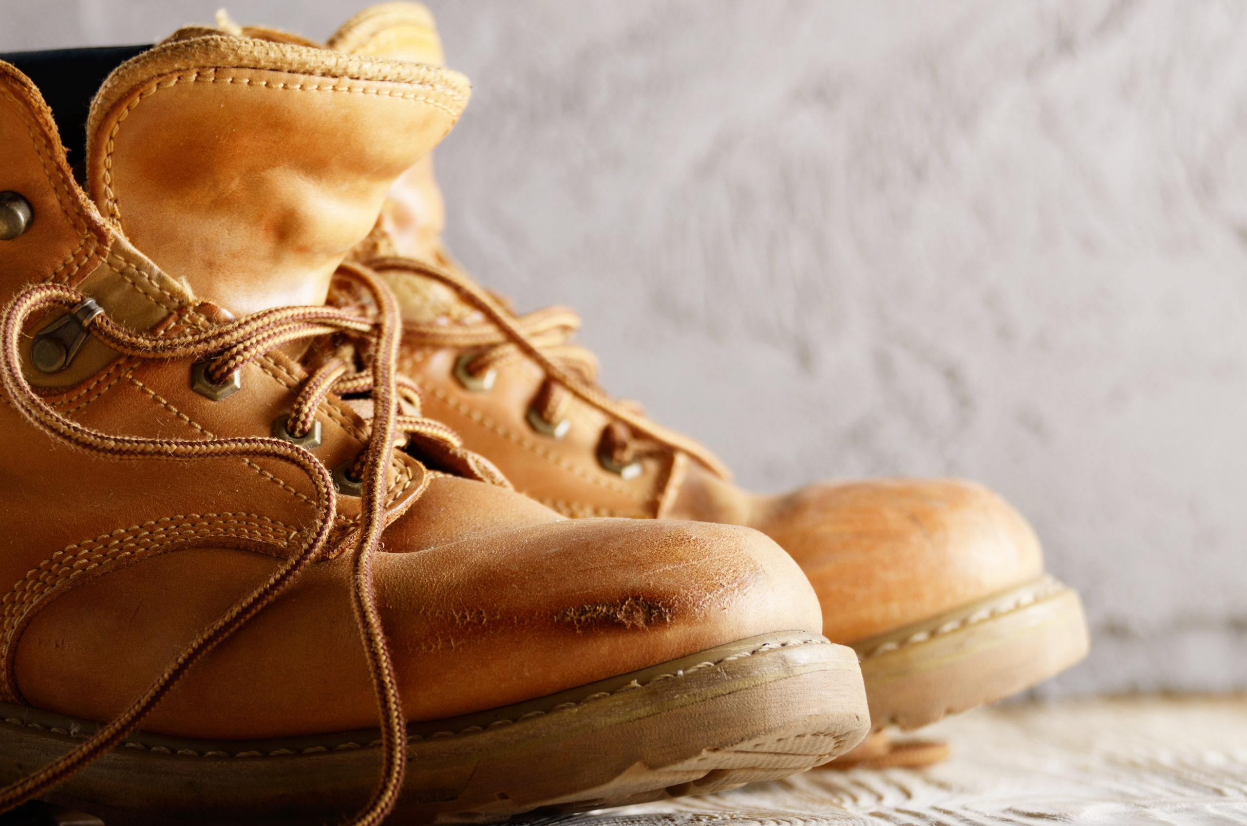 Yellow leather used work boots on concrete background closeup. P